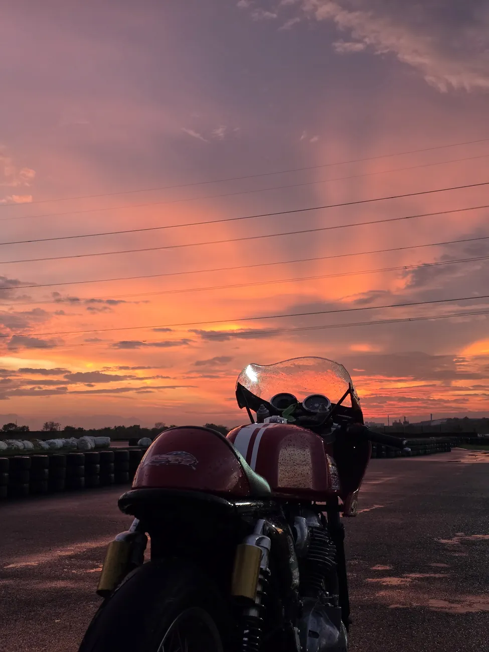Cafe racer against a burning dusk sky on wet tarmac